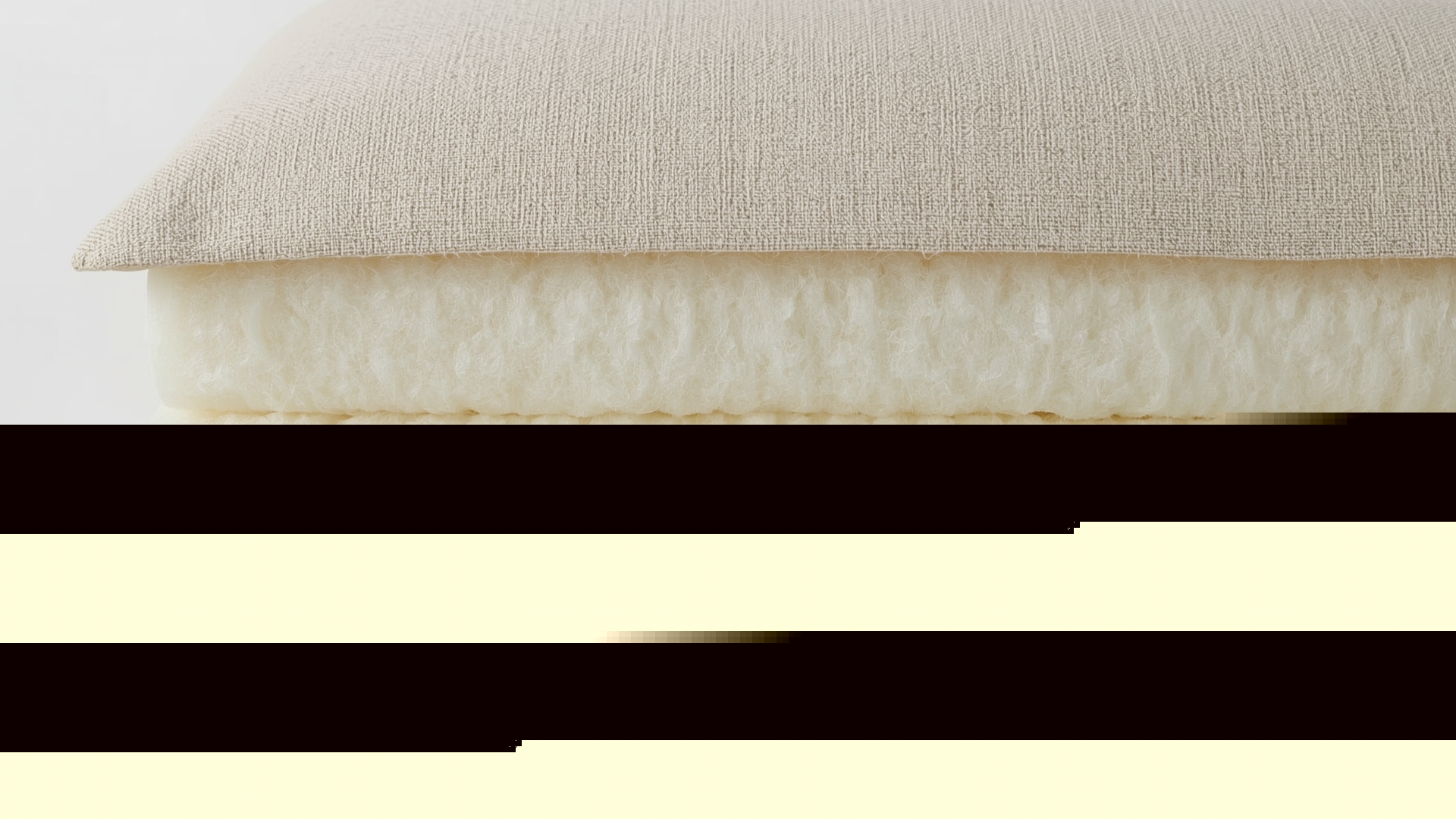 Cross-section macro view of hybrid sofa cushion showing foam core and polyester wrap layers inside fabric cover